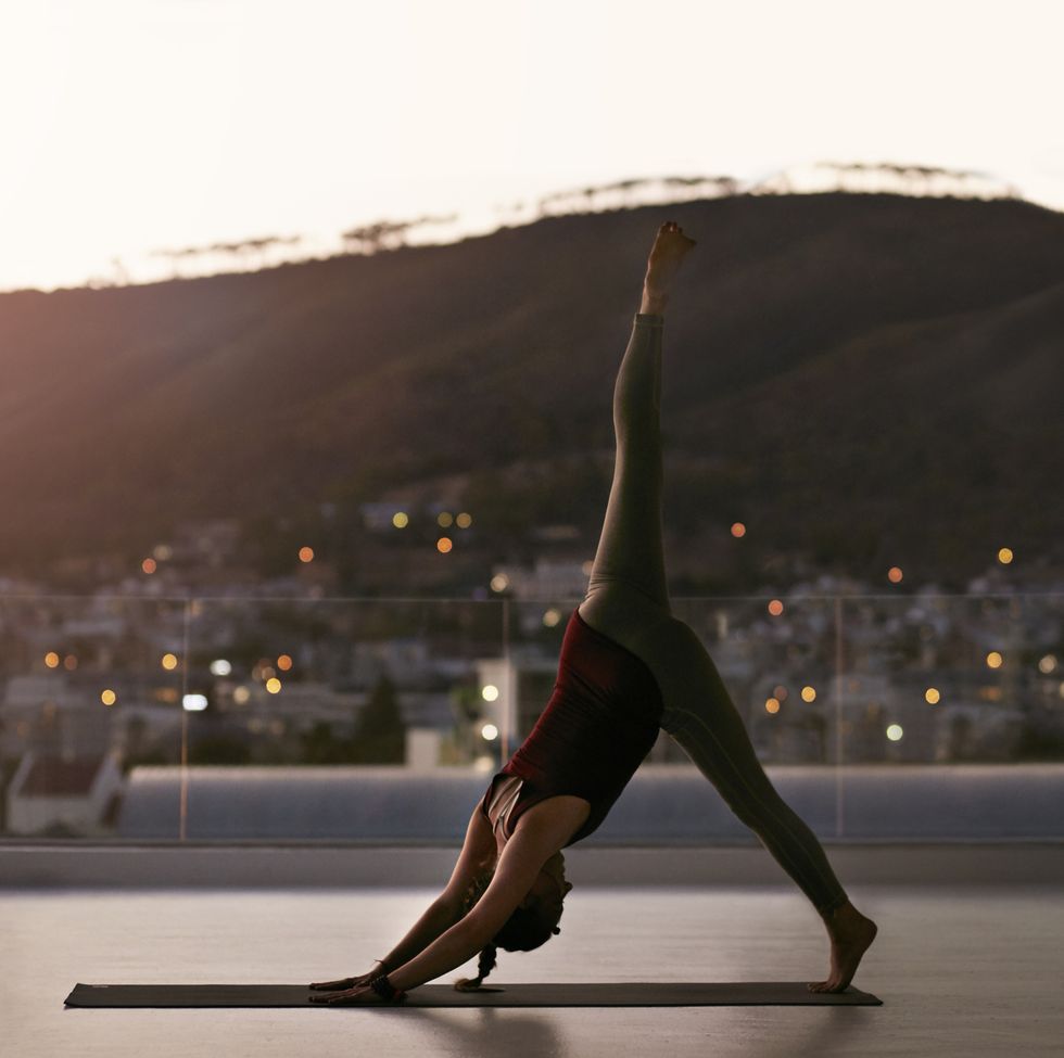 Woman stretching on yoga mat, at sunset