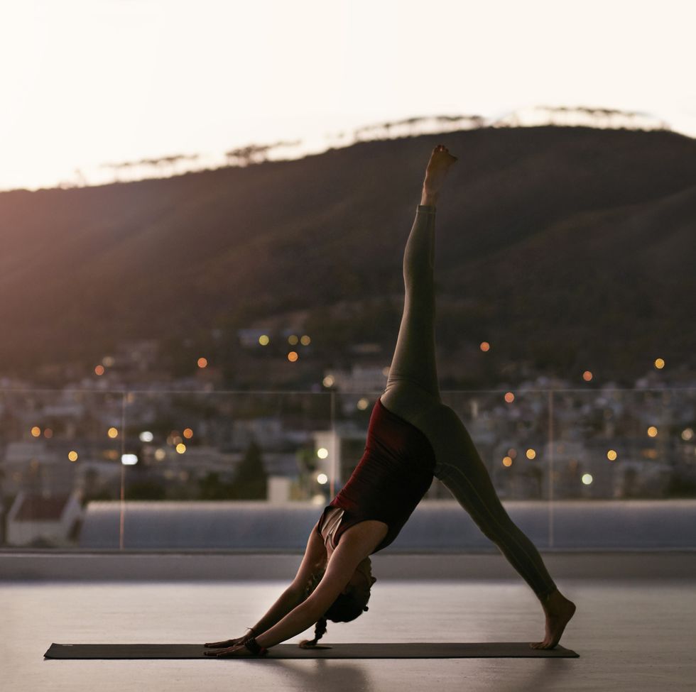 Woman stretching on yoga mat, at sunset