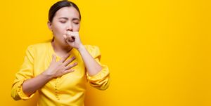 woman suffering from cold against yellow background