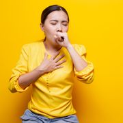 woman suffering from cold against yellow background