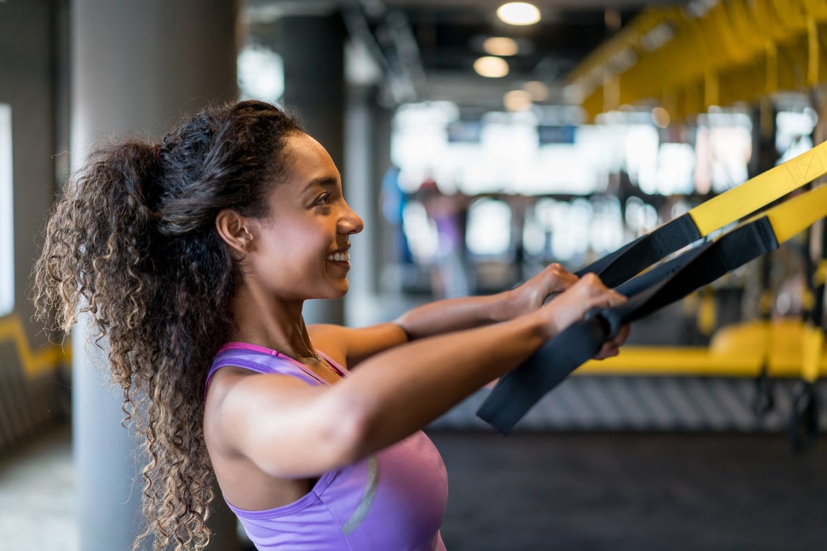 A dedicated female gym-goer focuses on her workout, pushing