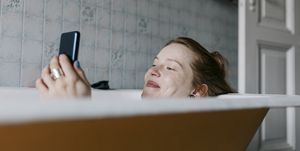 vrouw neemt bad en gebruikt telefoon