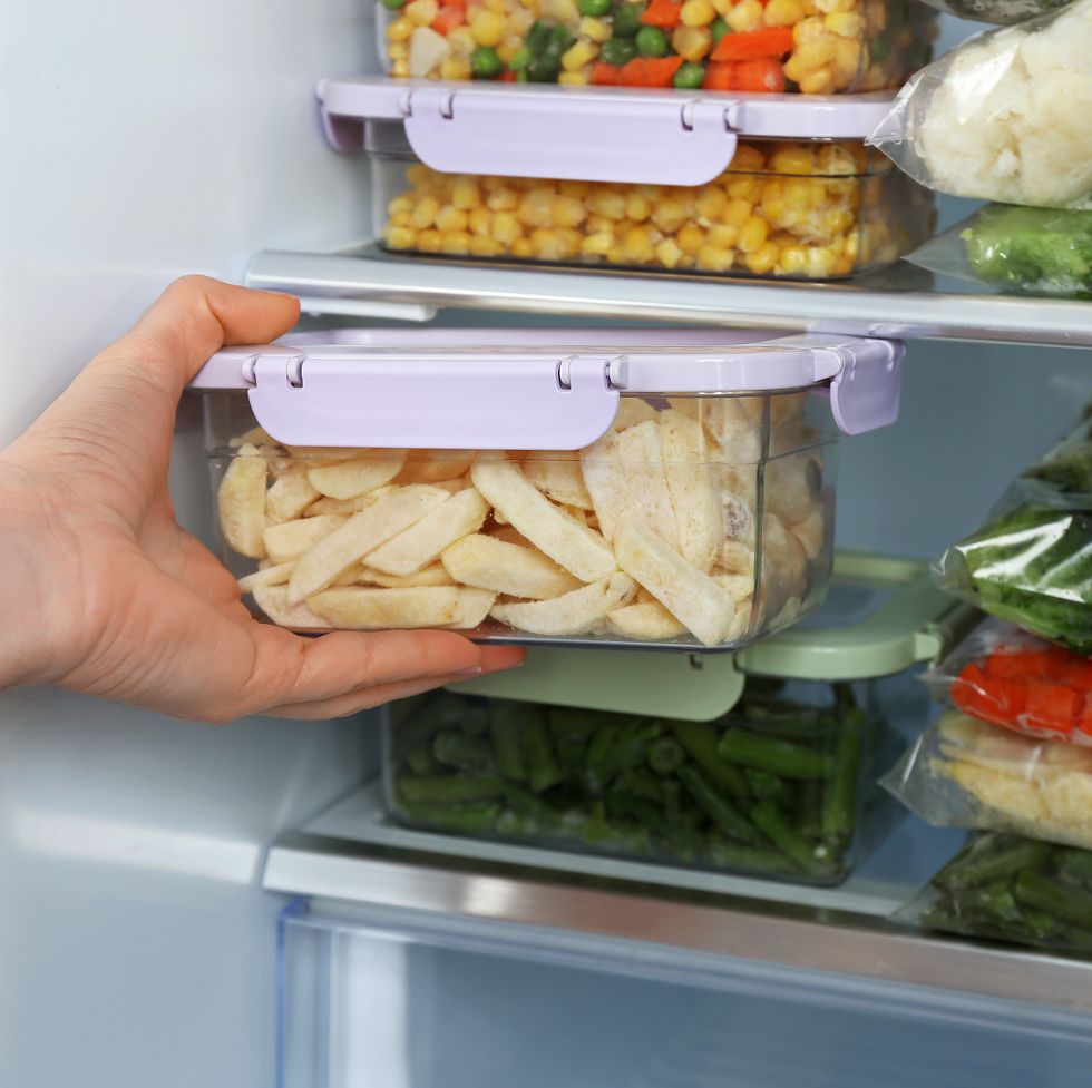 woman taking container with frozen potato from refrigerator, closeup