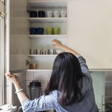 woman taking cups out from shelf