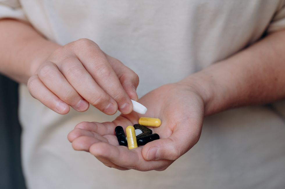 woman taking her vitamins and supplements, variety of pills and capsules in hands