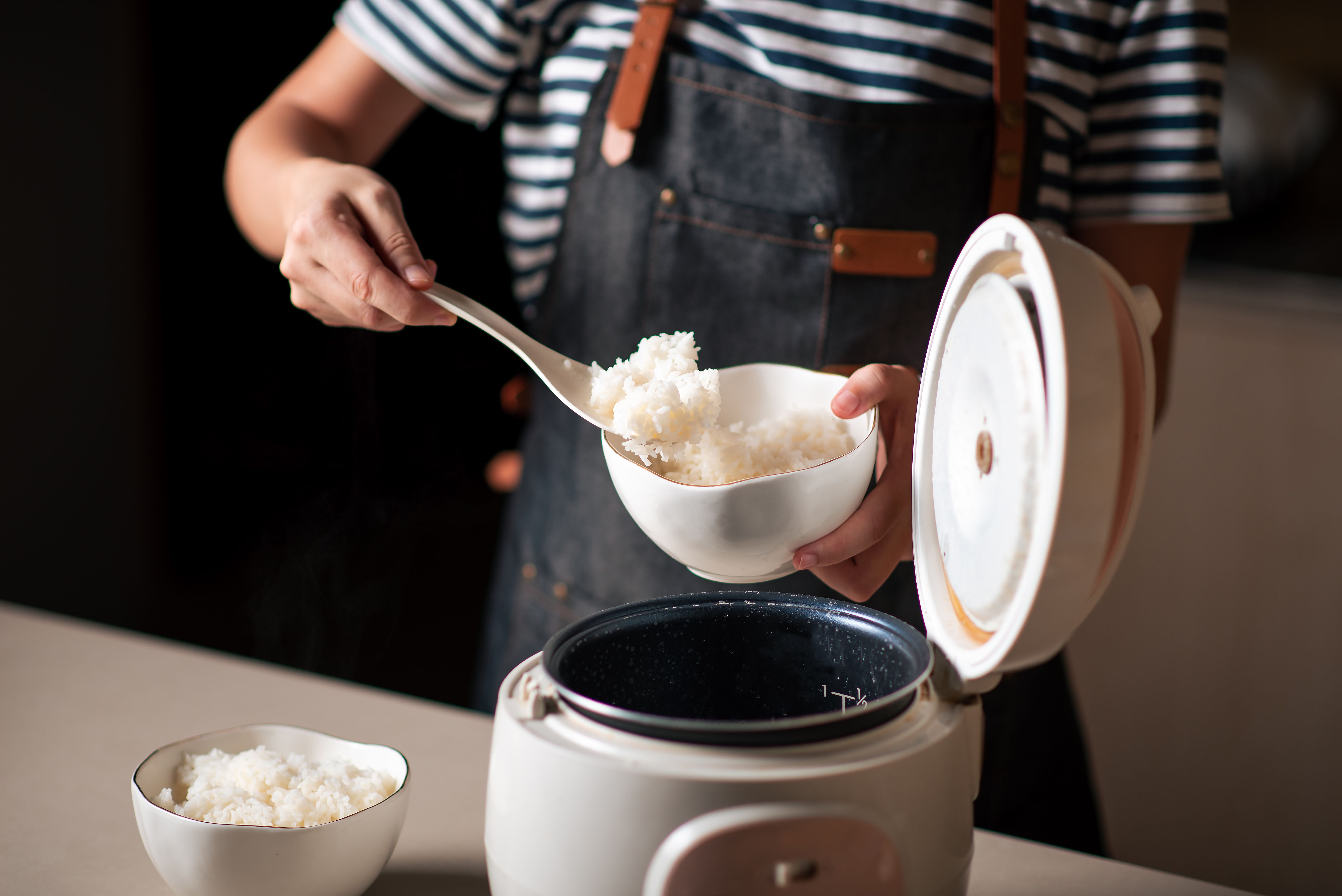 https://hips.hearstapps.com/hmg-prod/images/woman-taking-out-and-serving-fresh-boiled-rice-from-royalty-free-image-1651258733.jpg
