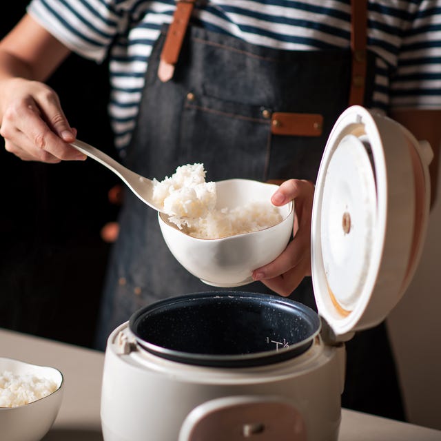 woman taking out and serving fresh boiled rice from the cooker