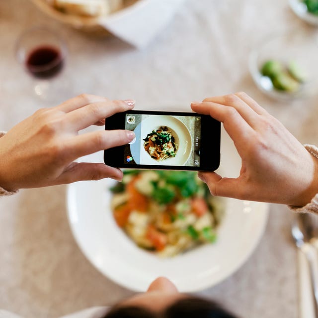 woman taking overhead photo of dinner