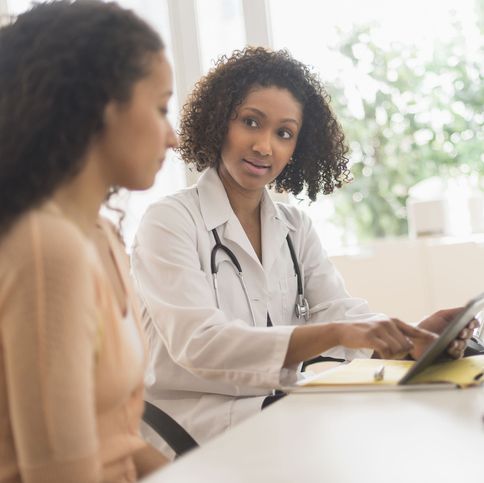 black female doctor and patient sitting together looking at a tablet