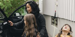 Woman teaching daughter to charge electric car at charging station