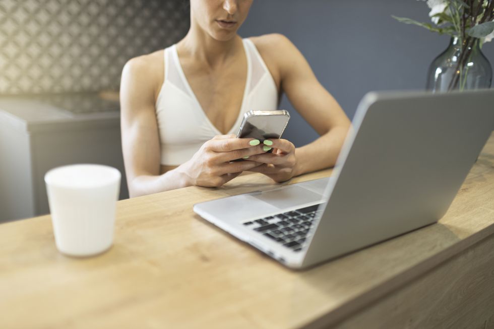 woman texting on smartphone and working on laptop