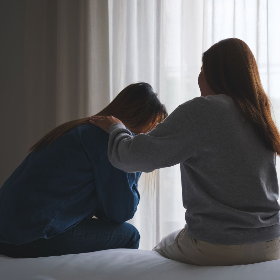 a woman touching her friend shoulder to comforting and giving encouragement in bedroom