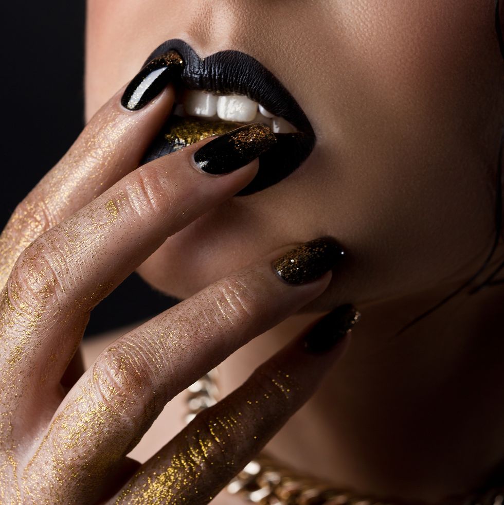 woman touching lips with black painted fingernails