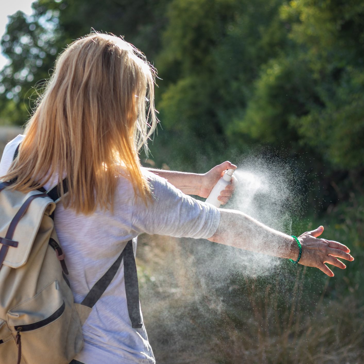 woman tourist applying mosquito repellent on hand during hike in nature insect repellent