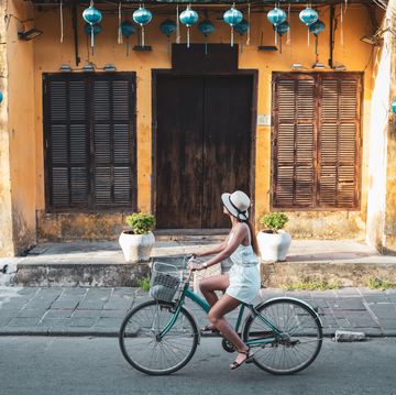 Woman tourist cycling in the old district of Hoi An in Vietnam during day .
