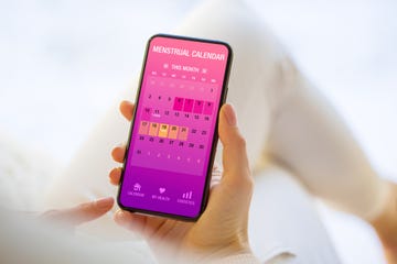 woman tracking periods by using menstrual calendar app on phone