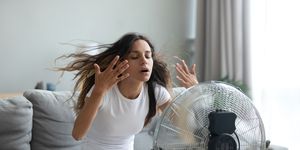 woman turned on fan waving her hands to cool herself