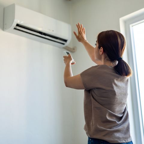 woman turning on air conditioner