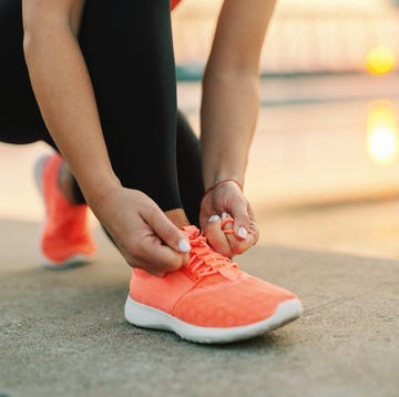 woman tying sneaker shoelace woman tying sneaker shoelace