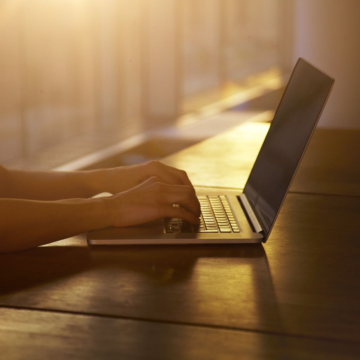 woman typing as the sun sets behind her