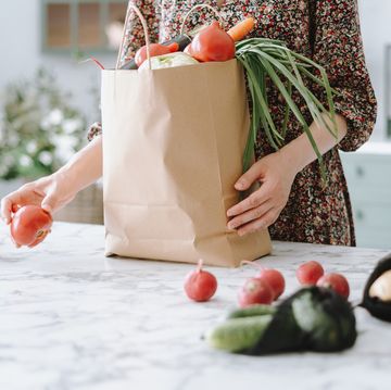 woman unpacking vegetables from paper grocery bag