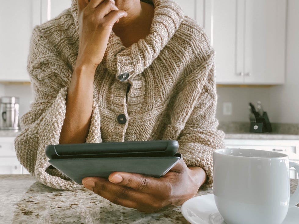 mujer abrigada usa una tablet en la cocina