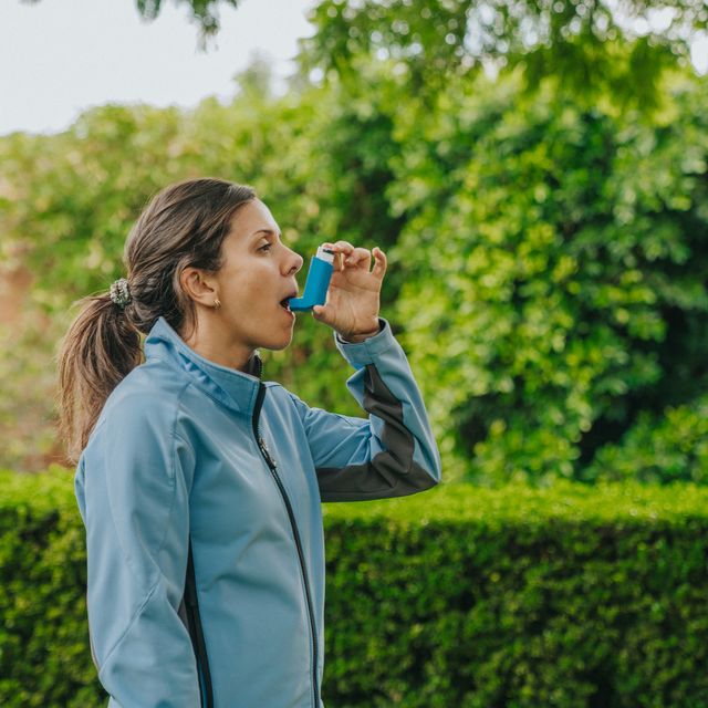 woman using asthma inhaler outdoors