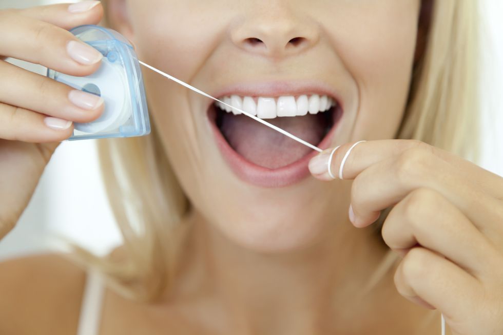 woman using dental floss, cropped