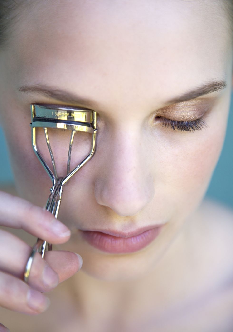 Woman using eyelash curler, close-up