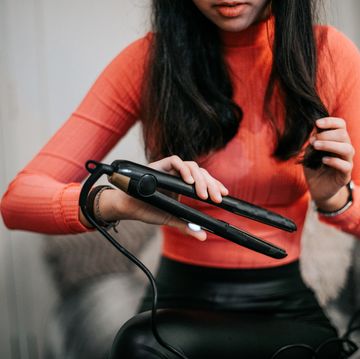 woman using hair straightener at home
