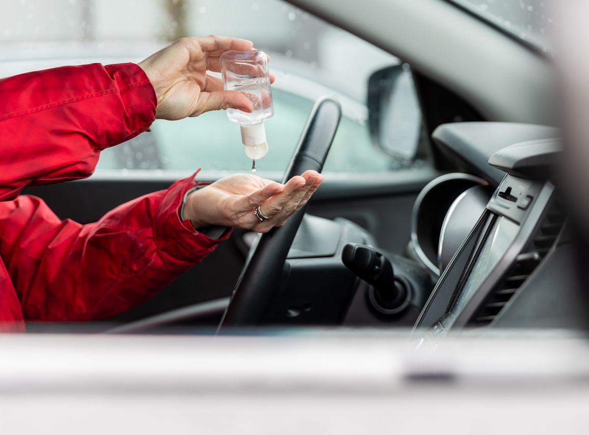 woman using hand sanitizer while sitting in car