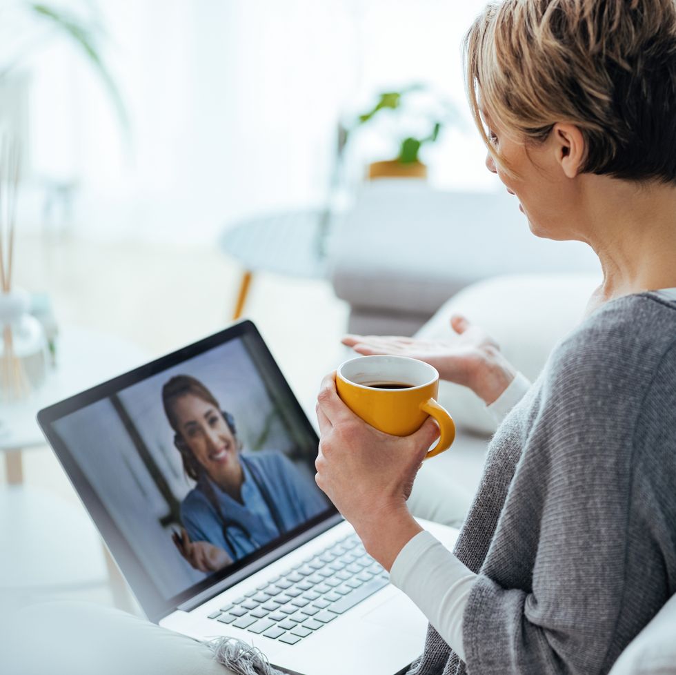 woman using laptop and having video call with her doctor while sitting at home