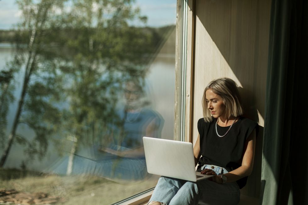 woman using laptop near window