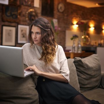 Woman using laptop on couch at home