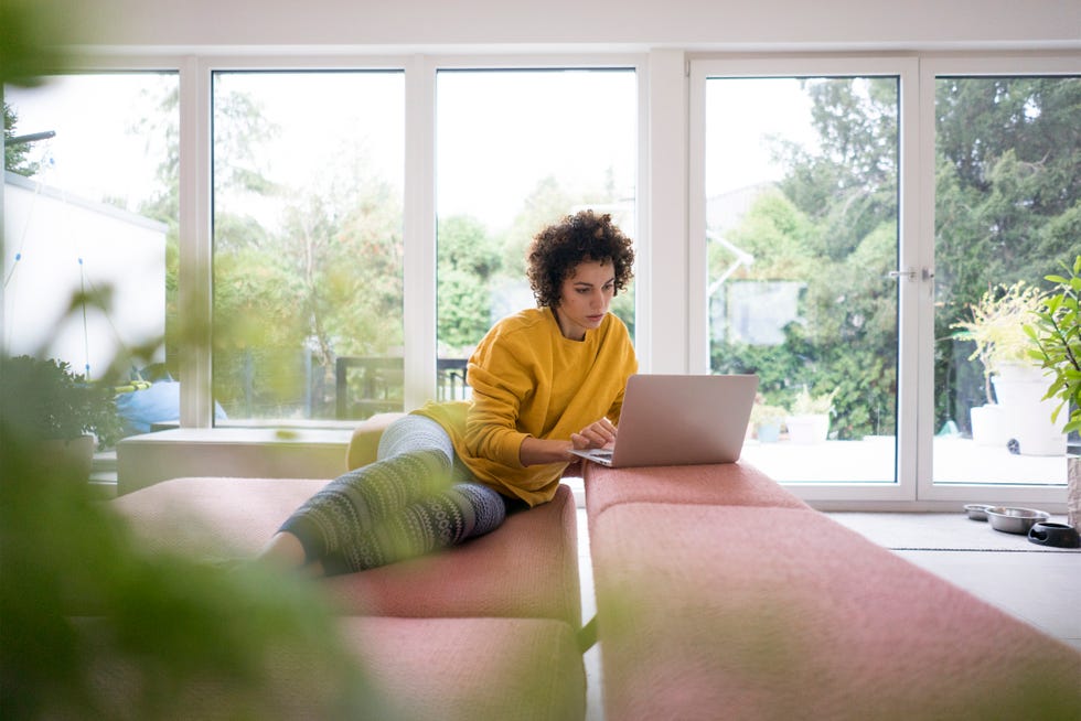 virtual birthday party ideas- Woman using laptop on couch at home