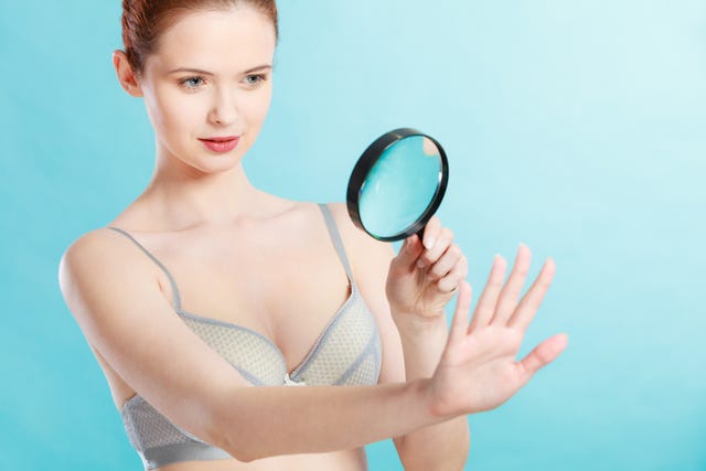 woman using magnifying glass to examine her moles skin