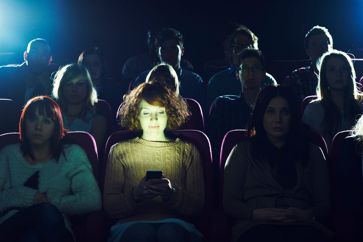 woman using phone during movie at cinema
