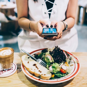 woman using smartphone while she is having lunch and coffee in a restaurant