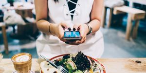woman using smartphone while she is having lunch and coffee in a restaurant