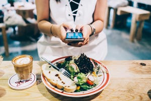 woman using smartphone while she is having lunch and coffee in a restaurant