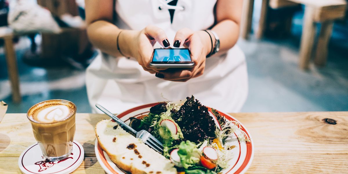 woman using smartphone while she is having lunch and coffee in a restaurant