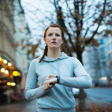 Woman using watch before exercising on sidewalk