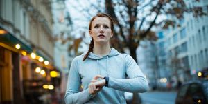 Woman using watch before exercising on sidewalk