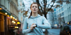 woman using watch before exercising on sidewalk