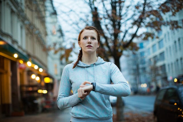 woman using watch before exercising on sidewalk