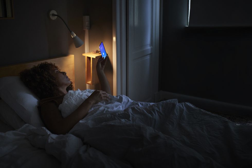 woman waking up through alarm ring on smart phone