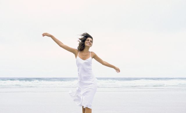 mujer paseando por la playa con vestido blanco