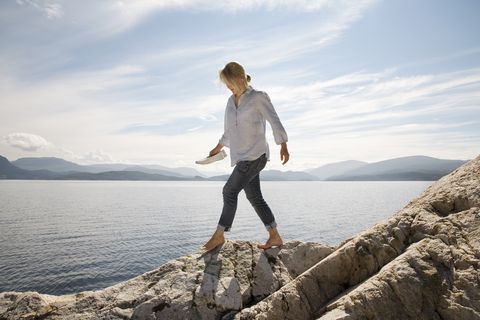 woman walking on rocky beach by sea