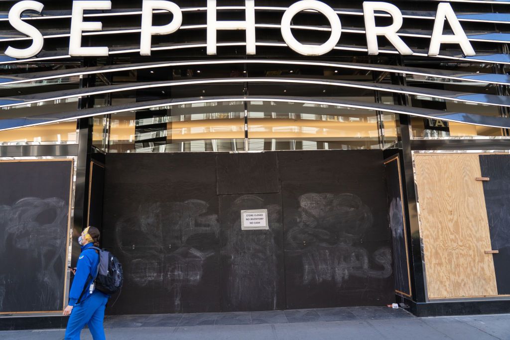 a woman walks past a boarded up sephora store in herald