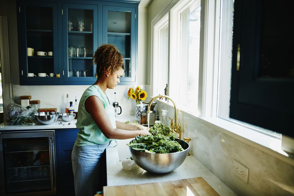 woman washing organic kale in kitchen sink